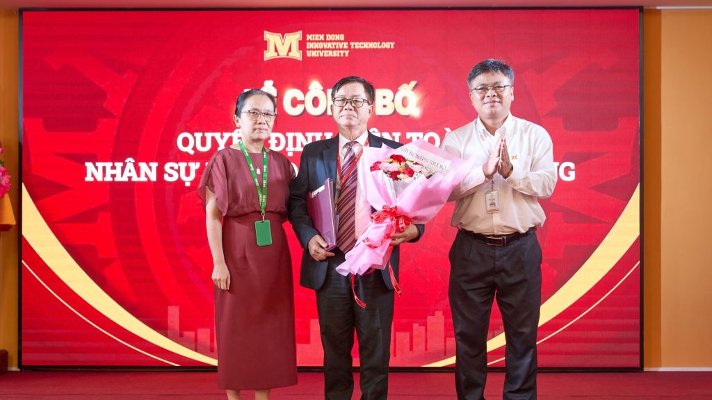 Bà Hoàng Thị Lệ Trinh - Phó Chủ tịch Hội đồng trường trao quyết định và PGS.TS. Phạm Văn Song - Hiệu trưởng Nhà trường trao hoa chúc mừng Chủ tịch Hội đồng trường PGS.TS. Nguyễn Bá Hoàng